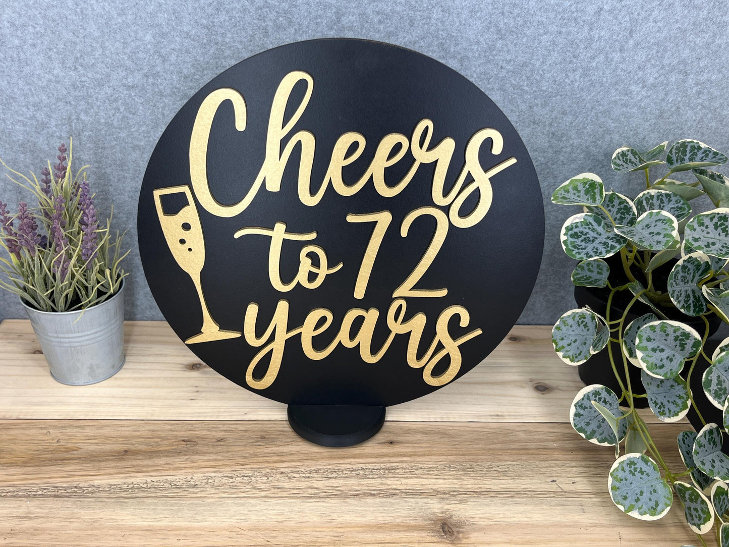 a sign that says cheers to 72 years next to a potted plant