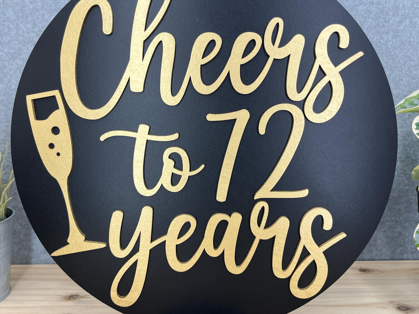 a black and gold sign that says cheers to 72 years