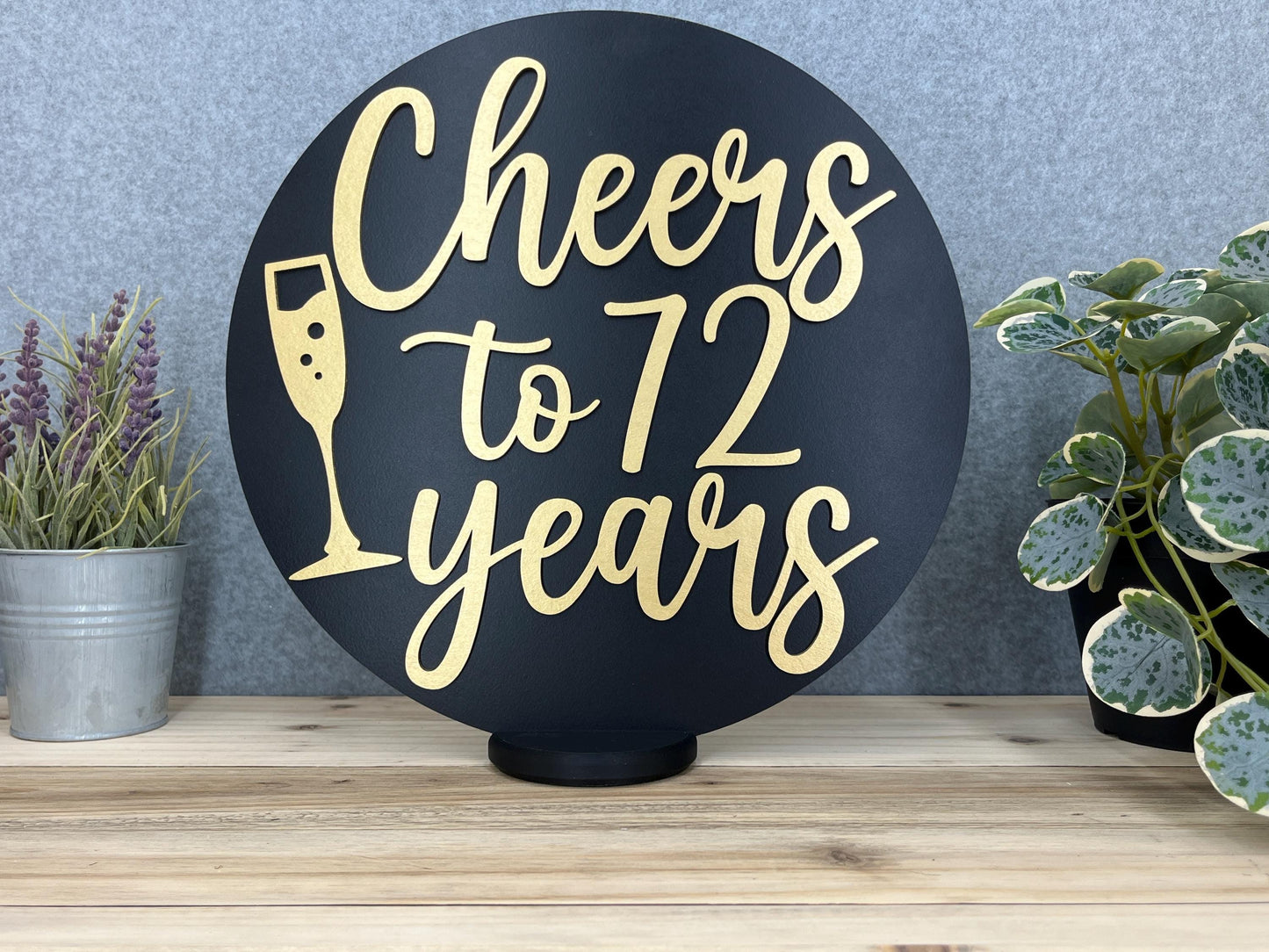 a sign that says cheers to 72 years next to a potted plant