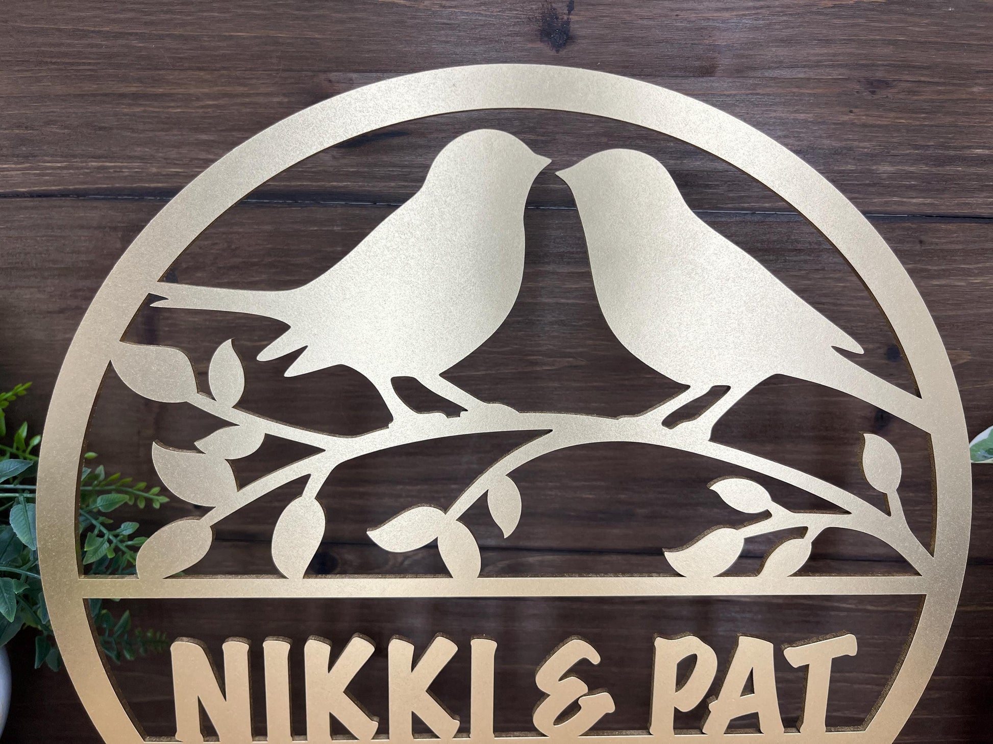 a metal sign with two birds sitting on a branch