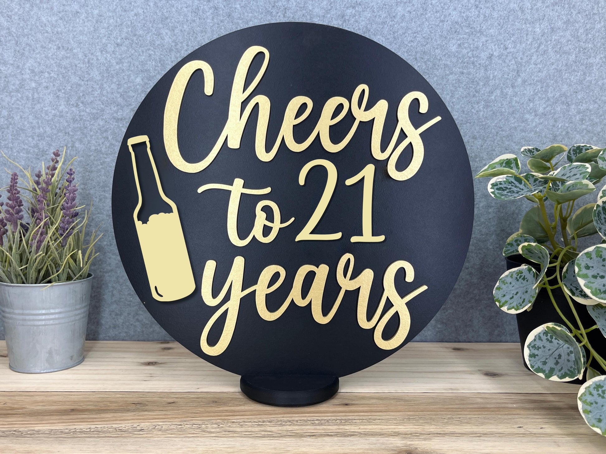 a sign that says cheers to 21 years next to a potted plant